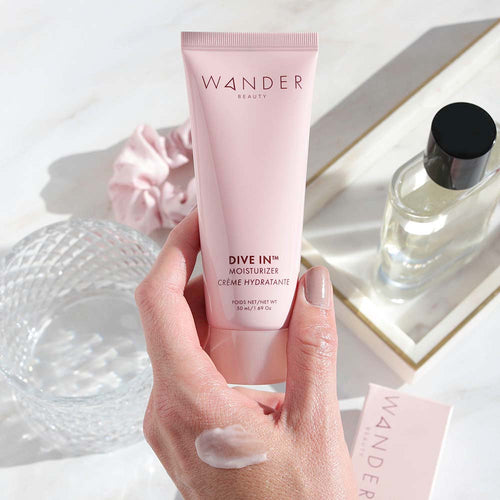 Hand holding Wander Beauty Dive In™ Moisturizer with formula swiped on hand